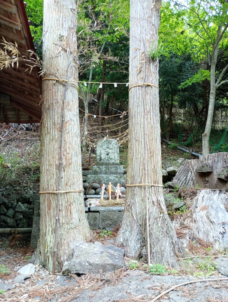 鳥居のような二本の木の向こうに双体道祖神が。ちょっと可愛い感じ。